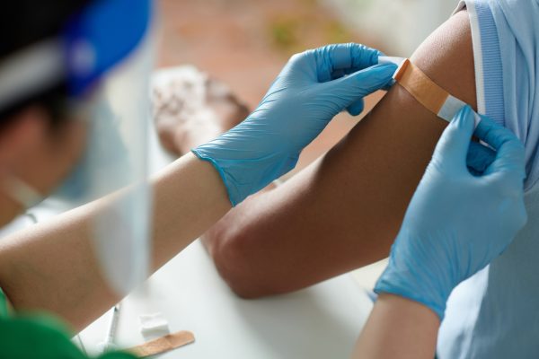 Nurse Sticking Bandage on Shoulder